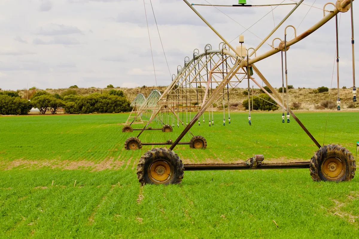 An advanced irrigation system waters a lush green field under a cloudy sky, enhancing farming efficiency.