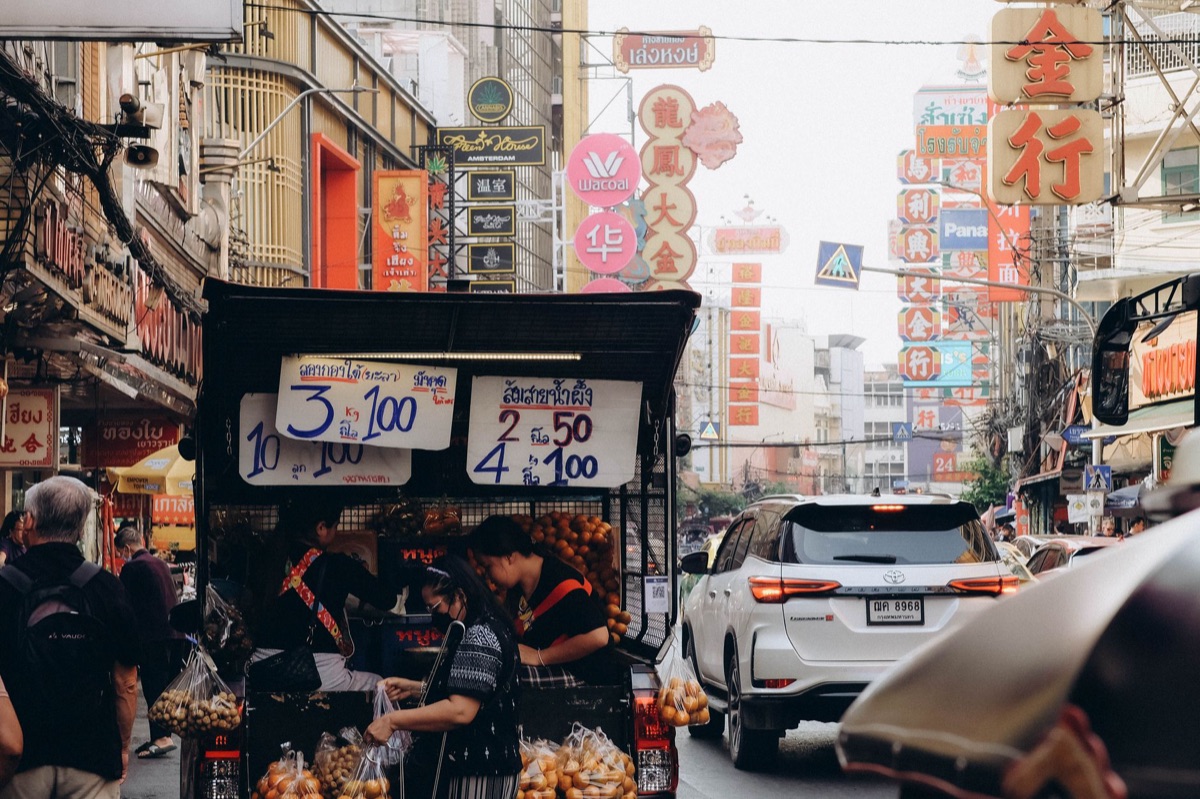 família thailandesa em mercado com frutas e cão
