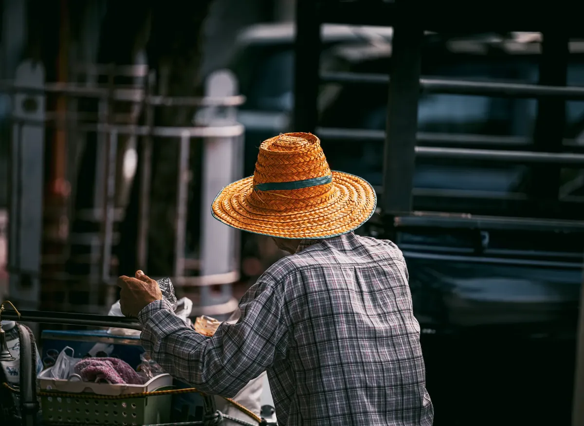 Rear view of a street vendor wearing a straw hat in Bangkok, Thailand.