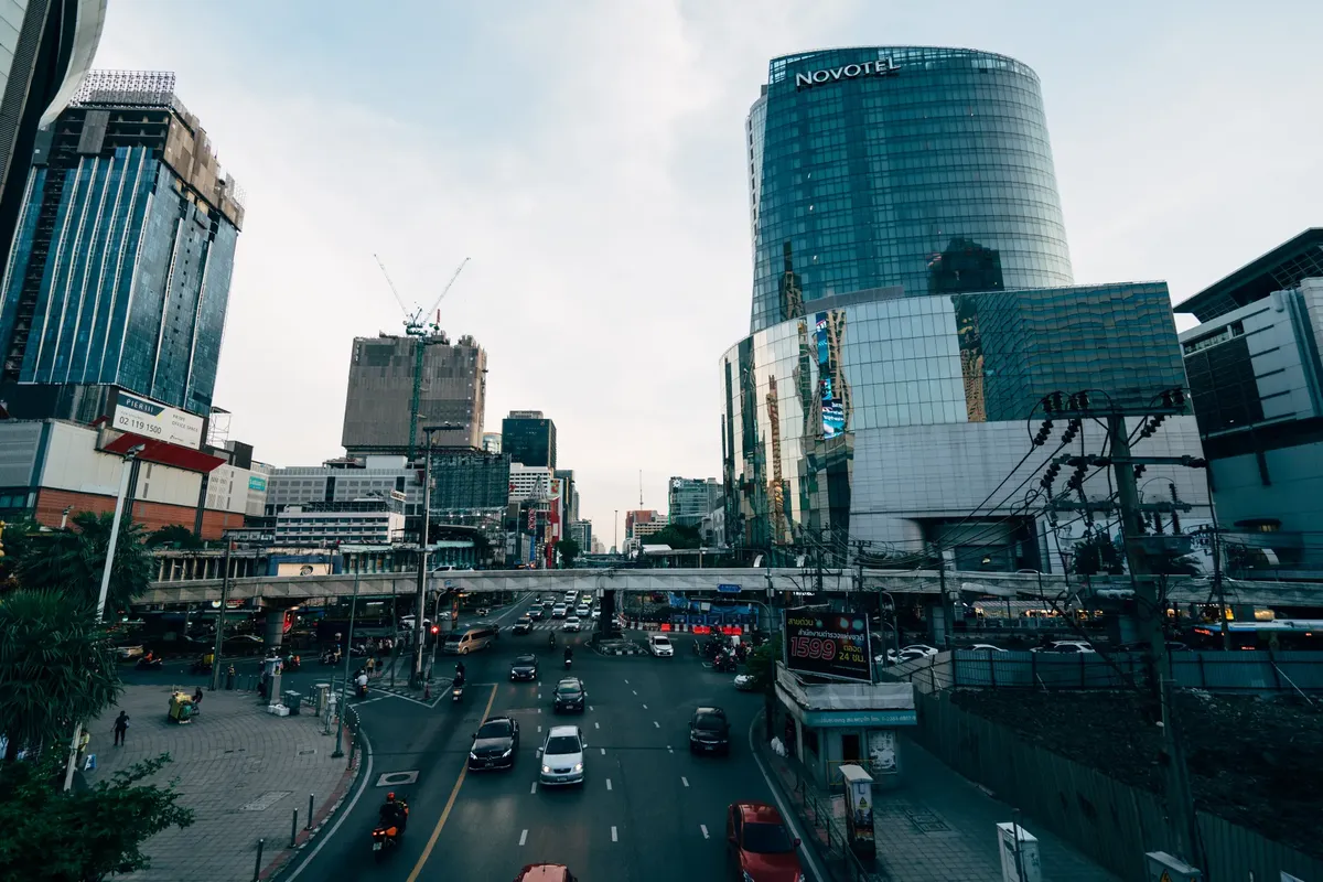 A busy Bangkok street with modern glass buildings and heavy traffic.