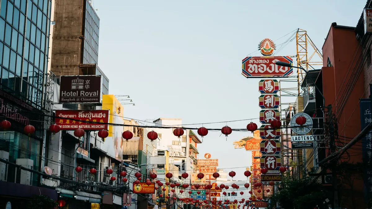 Lively street scene in Chinatown, Bangkok with traditional red lanterns and colorful signage.