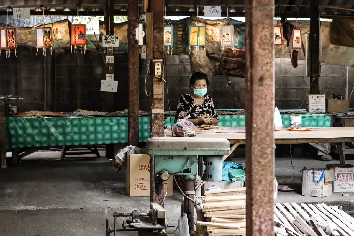 Elderly Asian woman with face mask in a market setting during pandemic.