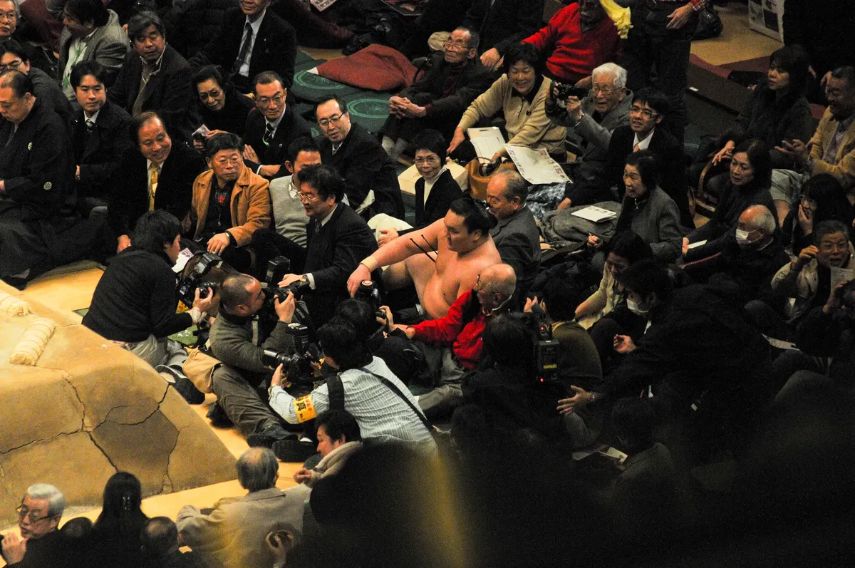 Sumo wrestling event with photographers capturing the scene, vibrant cultural moment.
